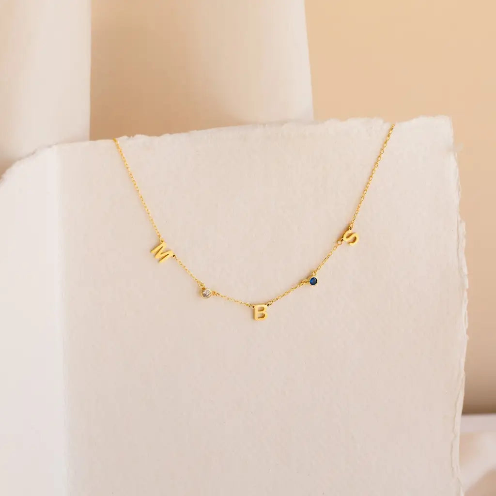 Our distinctive Birthstone Name Necklace is ethically crafted in real genuine gold by our skilled jewelers in Dubai. A truly lovely gift. Your loved one's name in gold, enhanced with their birthstone, creating a uniquely, personal gift. Gift a memory keeper for life. Designed in the United Arab Emirates.