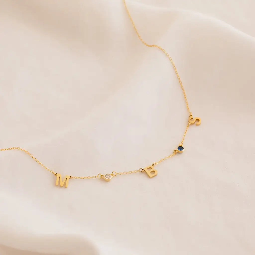Our distinctive Birthstone Name Necklace is ethically crafted in real genuine gold by our skilled jewelers in Dubai. A truly lovely gift. Your loved one's name in gold, enhanced with their birthstone, creating a uniquely, personal gift. Gift a memory keeper for life. Designed in the United Arab Emirates.