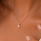 A delicate gold chain necklace with a small palm tree pendant, worn on a model's neck.