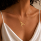 Woman wearing a personalised 18K gold Single Initial Necklace with letter A in yellow gold and white satin dress.