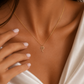 A delicate gold necklace with a small horse pendant worn by a model.