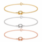 Three delicate chain bracelets with a central knot-like clasp are shown on a plain white background, in gold, silver, and rose gold tones.