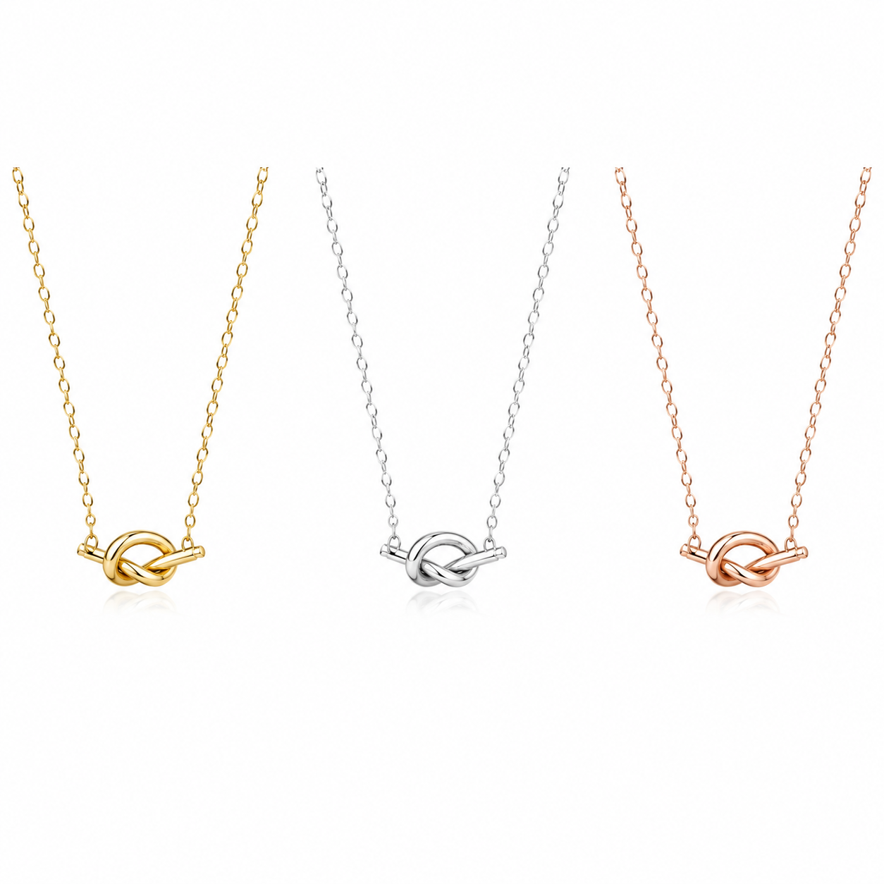 Three knot pendant necklaces on delicate chains, shown side by side in yellow gold, silver, and rose gold finishes against a plain white background.