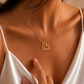 A close-up lifestyle shot of a woman wearing a delicate gold necklace with a cursive script pendant that reads 'Mia Noah'.