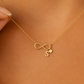 A delicate gold chain necklace featuring an infinity shaped pendant with heart and initial charm 
