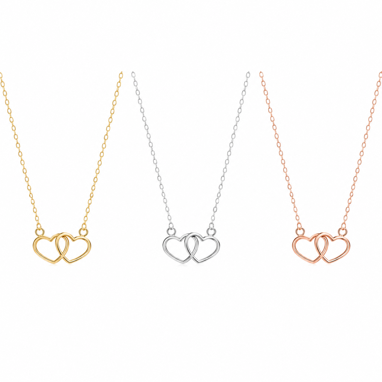 Three interlocking heart pendant necklaces on delicate chains, shown side by side in yellow gold, silver, and rose gold finishes against a plain white background.