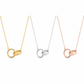 Three interlocking ring pendant necklaces on delicate chains, shown in gold, silver, and rose gold finishes against a plain white background.