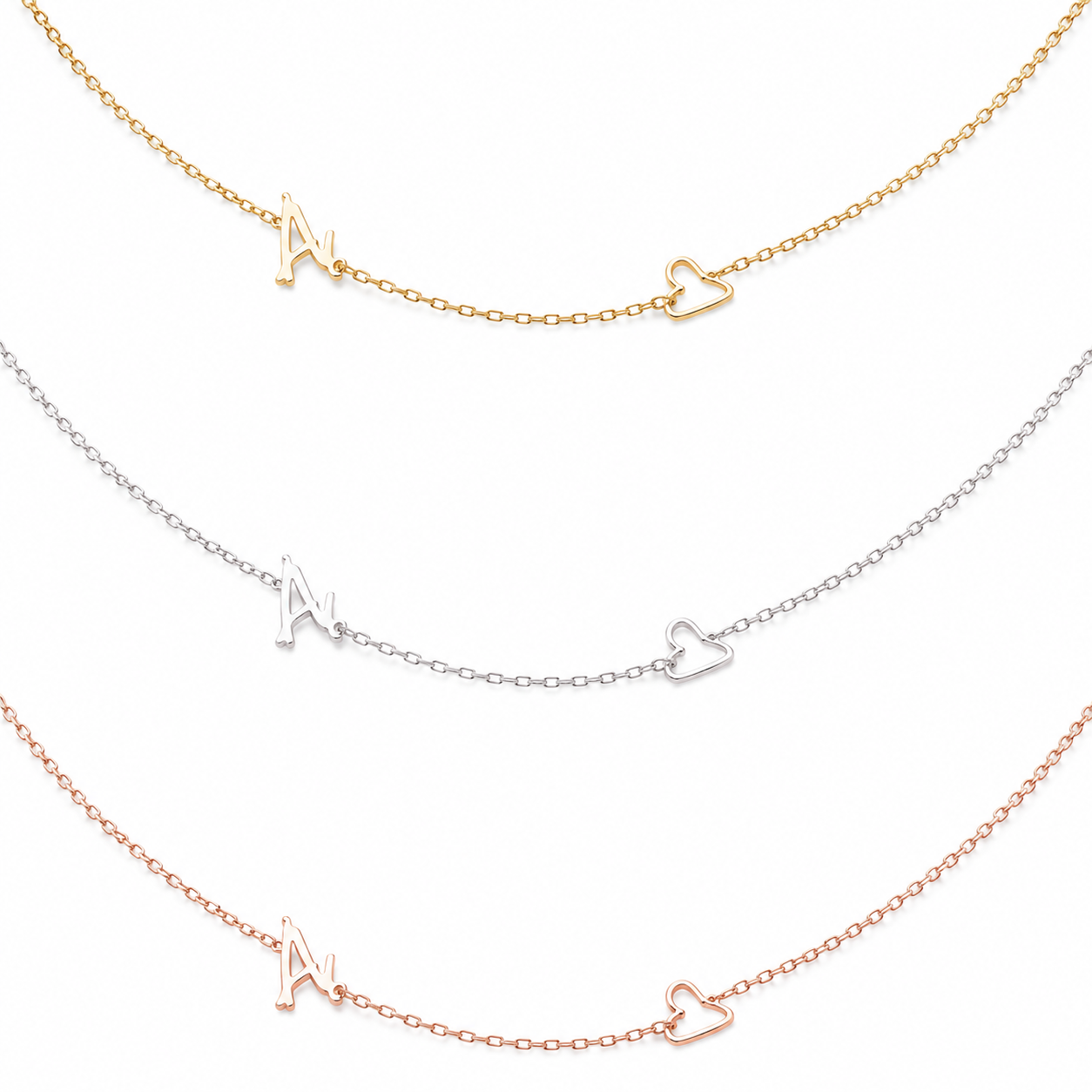 Three delicate necklace chains are shown on a white background, each featuring a small openwork letter M and a small openwork heart in different metal finishes: gold, silver, and rose gold.