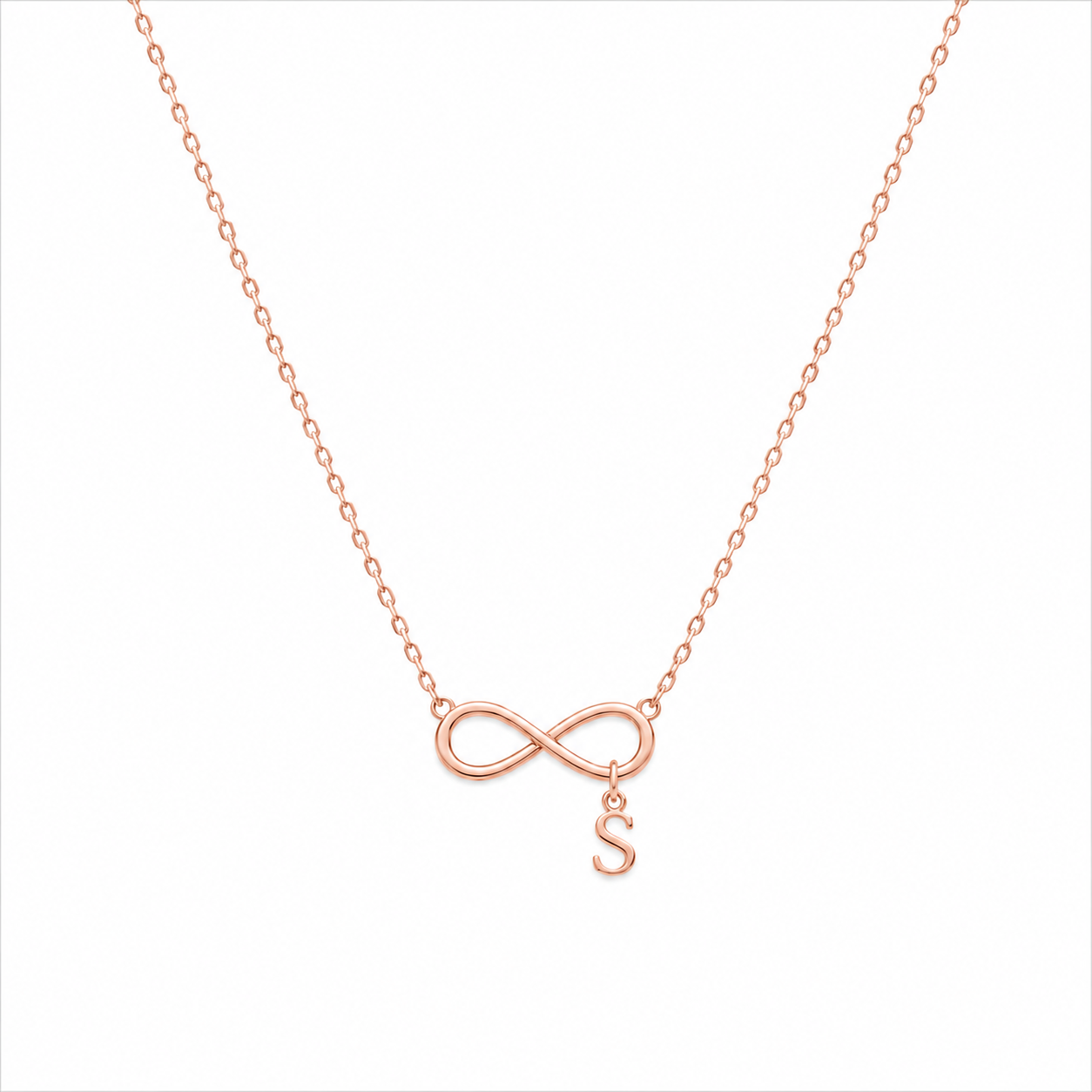 A delicate rose gold necklace featuring an infinity symbol pendant with a small dangling letter 'S', shown against a plain white background.