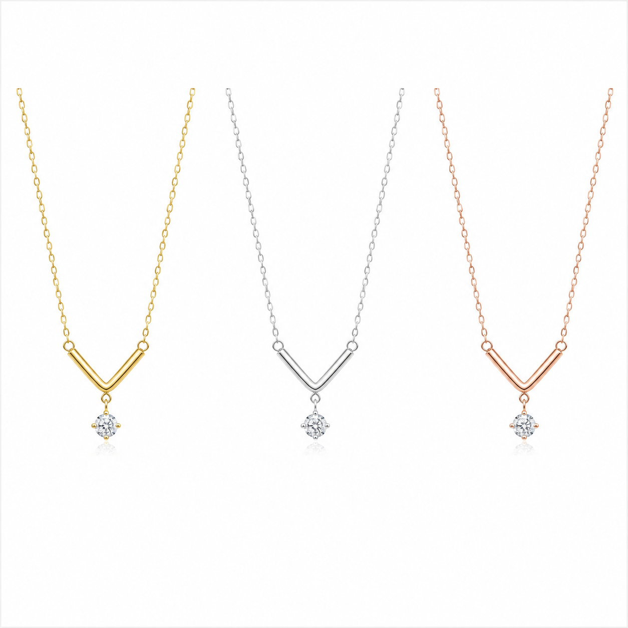 Three V-shaped pendant necklaces on a white background, shown in yellow gold, silver, and rose gold finishes, each with a clear gemstone pendant.