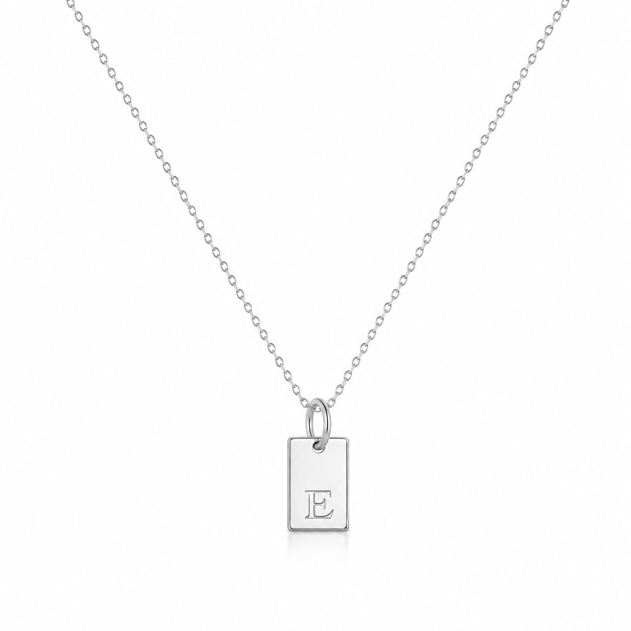 A white gold initial pendant necklace featuring a rectangular tag charm engraved with the letter 'E', suspended from a delicate cable chain on a white background.