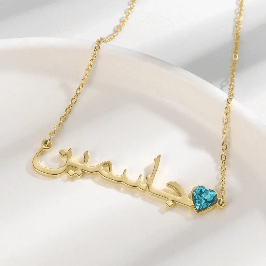 Simple yet eye-catching, this gold Arabic name necklace with birthstone is a stylish look anyone will appreciate. Our Name Necklace is a great piece that follows the fashion trend! Its fine curves and magnificent lettering make it a truly enjoyable necklace for you and your loved ones.   Made in Dubai, UAE.