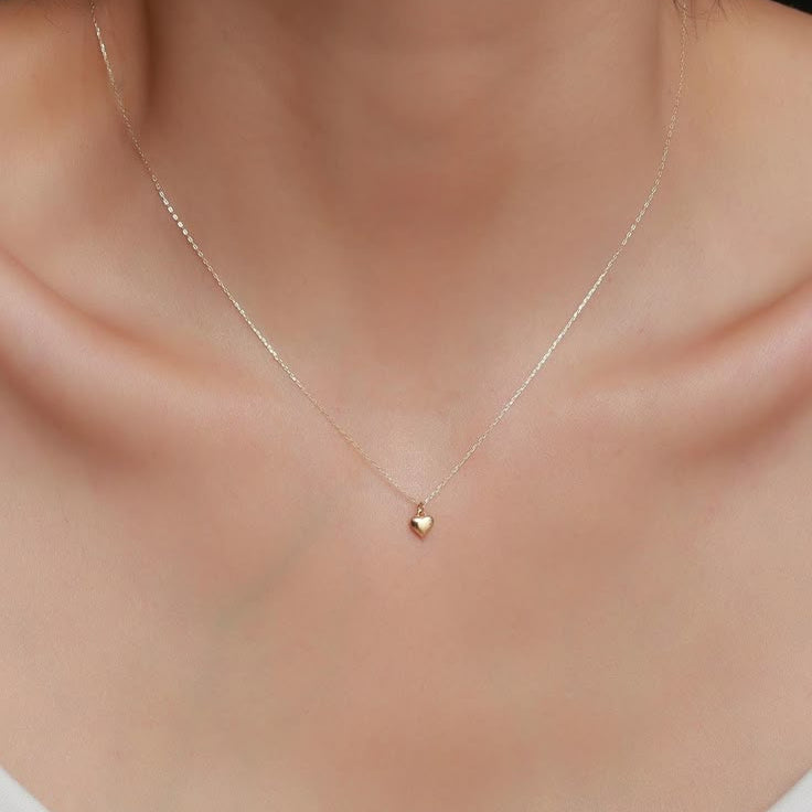 A delicate gold chain necklace with a small heart-shaped pendant.