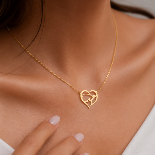 A close-up of a woman's neck and chest wearing a delicate gold chain necklace with an interlocking double-heart pendant.